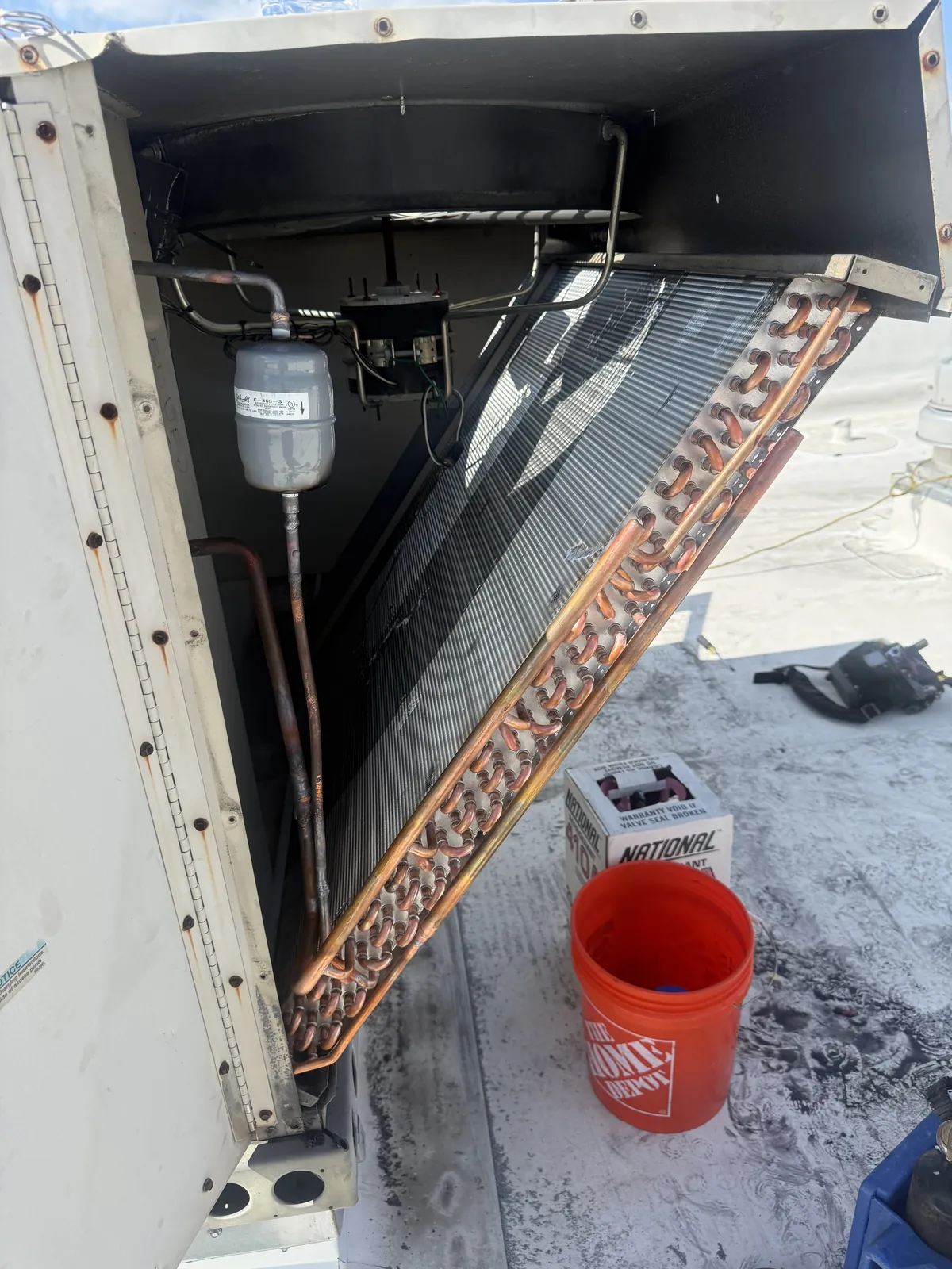 A Vice Mechanical technician servicing a dirty commercial refrigeration condenser coil